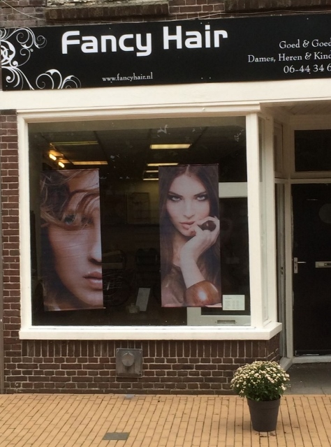 De gevel van Fancy Hair aan de Gasthuisstraat, met de zwarte luifel en de posters in de etalage